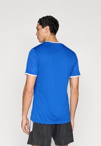 Camiseta deportiva azul de manga corta hecha de tela lisa, con cuello redondo, ribete blanco en las mangas y un corte holgado.