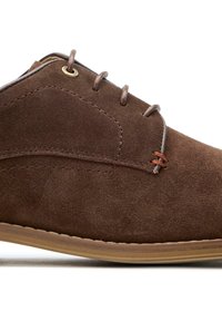 Brown suede shoe with a round toe, featuring tan laces and a small red accent. The sole is textured and beige, with subtle stitching details.