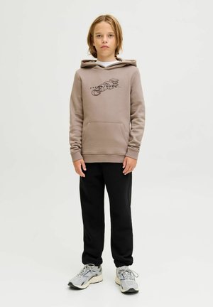 Felpa marrone con tasca frontale e stampa grafica, pantaloni della tuta neri e sneakers grigie. Design semplice, tessuto di peso medio, vestibilità rilassata.