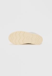 Sko såle med en teksturert, beige gummibunn som har et sikksakkmønster og preget logo. Øvre materiale i grått stoff.