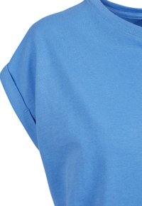 T-shirt en coton bleu clair à manches courtes avec des revers roulés et un col rond, présenté de l'épaule jusqu'à la partie supérieure de la poitrine.