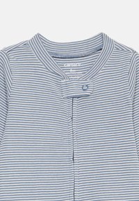 Gestreifte Babyjacke in Blau und Weiß aus weichem Baumwollmaterial, mit rundem Kragen, Knopfverschluss und feiner Rippstruktur.