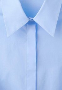 Svetlomodrá bavlnená košeľa s klasickým golierom, predným zapínaním a hladkou textúrou, s jemnými švami pre zvýšenú odolnosť.