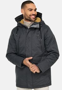 Chaqueta gris aislante con capucha, dos bolsillos en el pecho con cremallera y forro de forro polar. El diseño incluye cordones ajustables y cierre a presión.