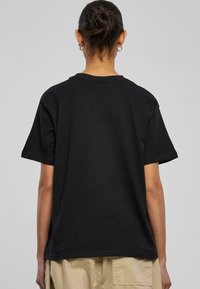 Sort bomulds T-shirt med korte ærmer, løs pasform og rund halsudskæring. Bagsiden er ensfarvet uden logoer eller mønstre.