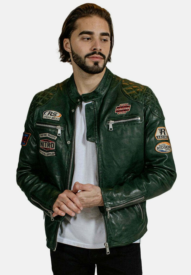Veste de moto en cuir vert avec un design de manches matelassées, plusieurs patchs, poches zippées et une silhouette ajustée.