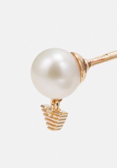 Pendientes dorados con una gran perla blanca en la parte superior y un diseño de espiral a rayas en la parte inferior, que destaca una mezcla de formas y texturas.