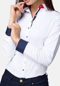 White button-up shirt with navy cuffs and collar accents, featuring a checkered pattern inside the collar. Smooth texture and fitted design.