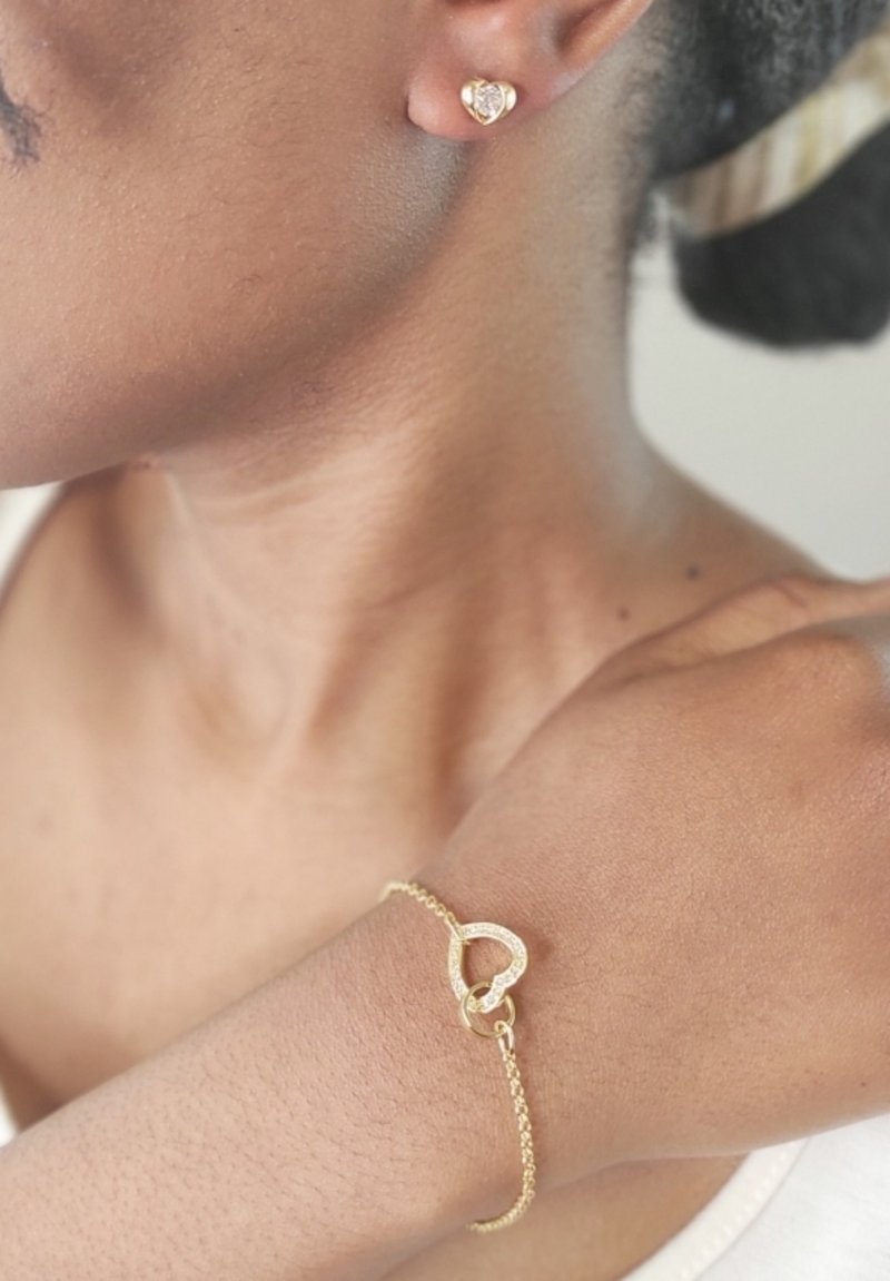 Orecchini a forma di cuore in oro e bracciale coordinato con catena, caratterizzati da un design a cuori collegati. Finitura liscia e lucida.