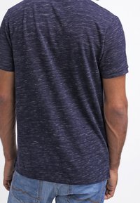 Marinblå kortärmad t-shirt med en texturerad, melerad mönstring. Mjukt tyg med rund halsringning, något figurnära vid axlarna.