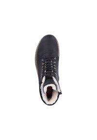 Black leather ankle boot with a textured finish, white faux fur lining, metal eyelets, and a round toe design. Features laces and a side zipper.