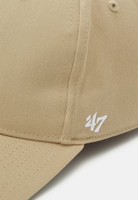 Beige cap with textured fabric, featuring a curved brim and white embroidered "47" logo on the side.
