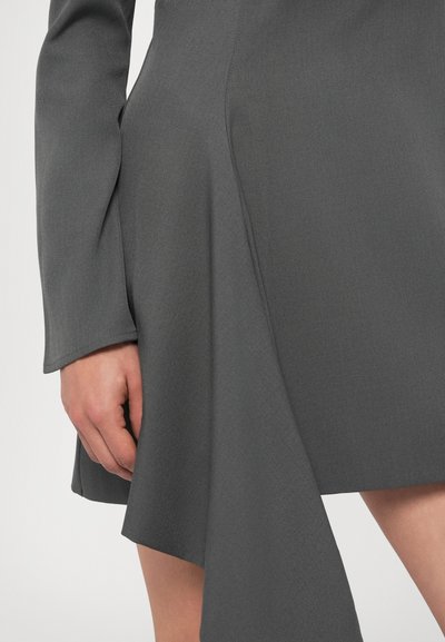 Hosszú ujjú, szürke ruha, redőzött dizájnnal és éles aszimmetrikus szegéllyel. Texturált anyagból készült.