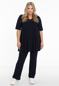 Ensemble de deux pièces bleu marine comprenant un haut à manches courtes et col en V avec des plis et un pantalon droit assorti, fabriqué dans un tissu doux.