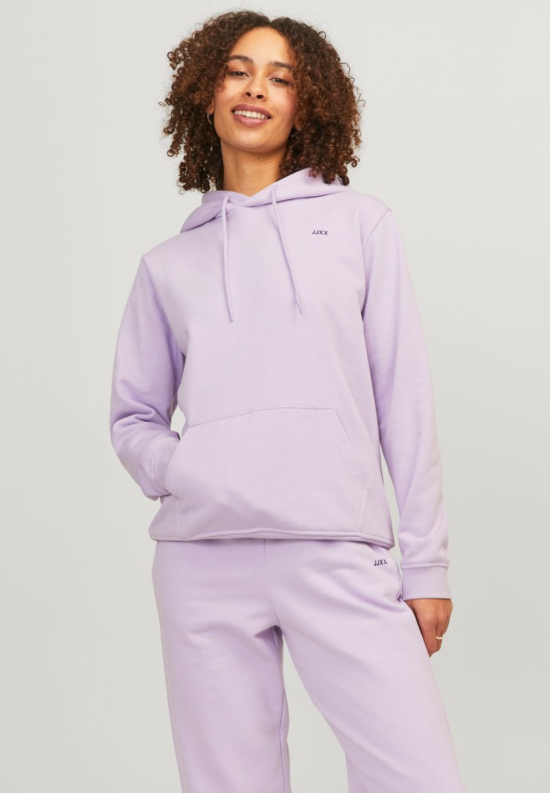 Felpa viola chiaro in morbido tessuto, con tasca a marsupio, cappuccio con cordino e piccolo logo sul petto. Abbinata a pantaloni coordinati.