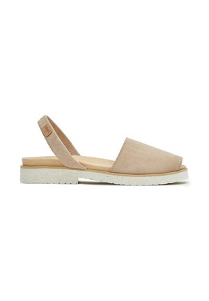 Zapato slingback de ante beige con una punta ancha y plana y una suela blanca texturizada. El diseño presenta un hardware mínimo y dos correas.