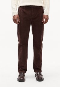 Brune kordfløjspants med lige pasform, der har en struktureret overflade og standard forlommer, parret med mørkebrune sko.