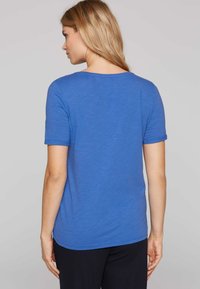 Camiseta azul de manga corta hecha de un tejido ligero, con un corte holgado y un escote redondeado. Textura suave, diseño minimalista.