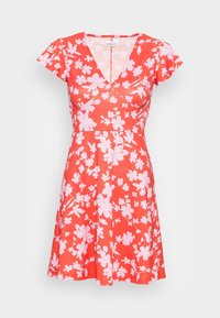 Robe fleurie rouge à manches courtes, décolleté en V et jupe évasée. Décorée de fleurs roses sur un fond uni. Tissu léger.