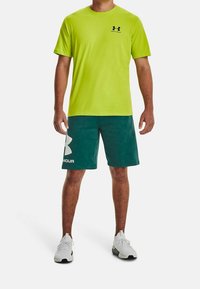 Zeleno-limetková košile s krátkým rukávem a tyrkysové kraťasy s bílým logem Under Armour. Nosit s bílými sportovními botami, hladká tkanina, volný střih.