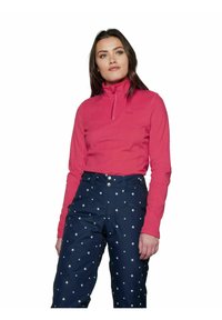 Pullover in pile di colore rosa brillante con collo alto e chiusura a zip. Pantaloni blu navy con motivo a stelle bianche e tasche multiple, dotati di bottoni.
