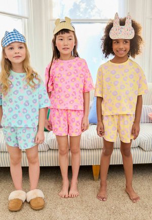 Drei Mädchen in bunten Freizeitanzügen: mintgrün, pink und gelb mit Leopardenmuster. Baumwollstoff, lockere Passform und passende Shorts.