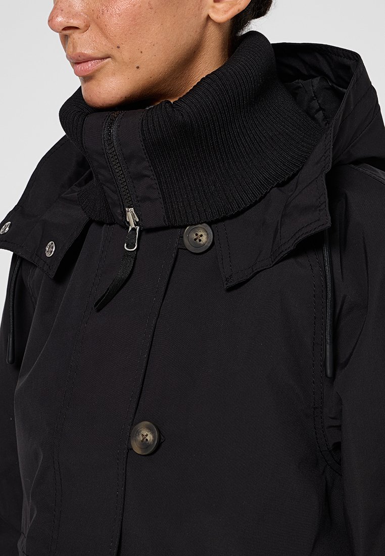 Schwarzer Wintermantel mit hohem, geripptem Kragen, Reißverschluss und Knopfdetails. Hergestellt aus glattem, strapazierfähigem Gewebe mit figurbetonter Silhouette.
