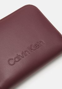 Calvin Klein EMBOSSED LOGO ZIP WALLET - Denarnica - oxblood