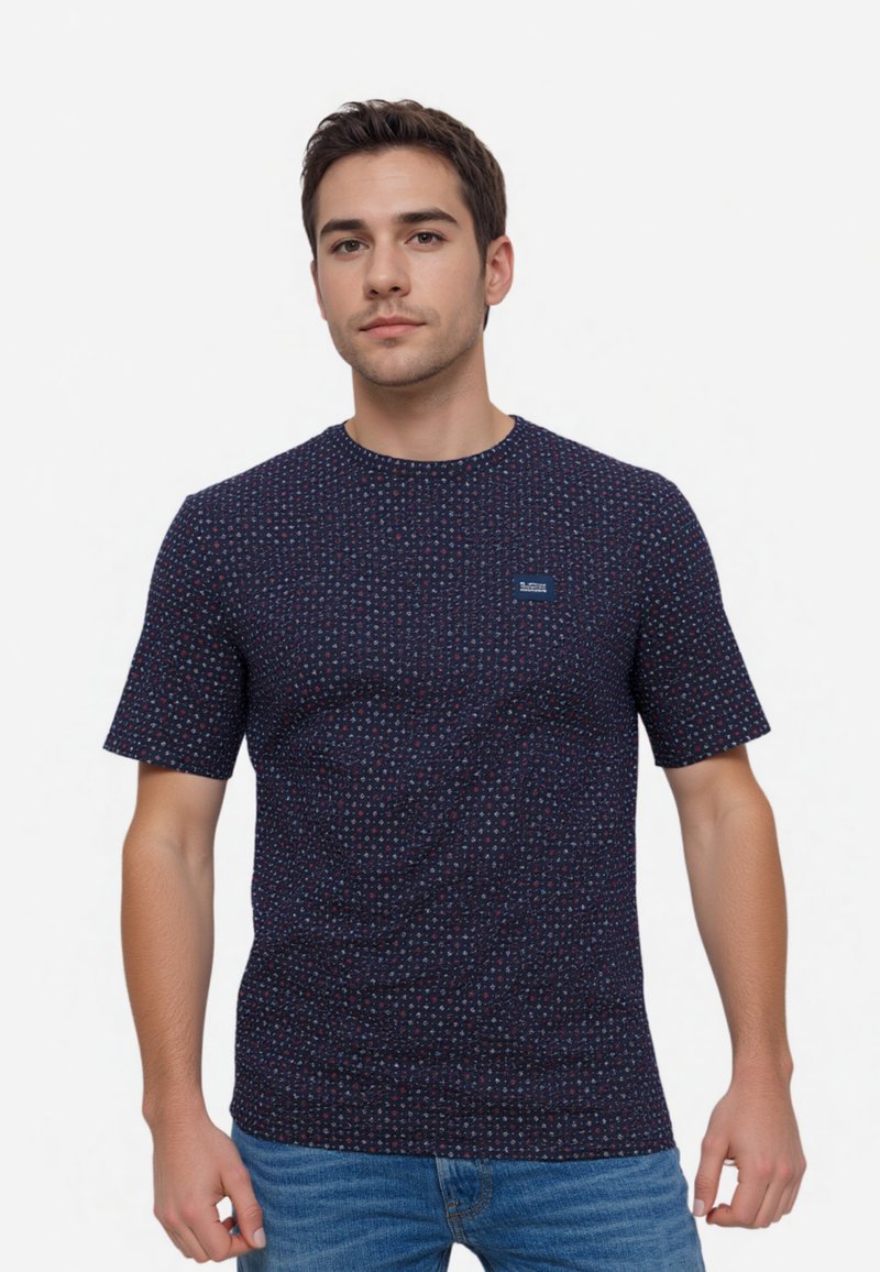 Navy blue t-shirt with a small logo, featuring a geometric dot pattern in red and white. Short sleeves and crew neckline, made of cotton.