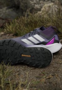 Scarpe sportive viola con strisce bianche, suola nera per la trazione e accenti viola. Presentano una parte superiore traspirante e gomma Continental per la presa.
