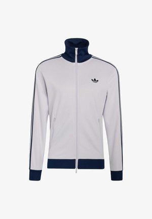Weißes Reißverschluss-Jacke mit marineblauem Kragen, Bündchen und Saum, mit schwarzen Streifen an den Ärmeln und einem schwarzen Adidas-Logo auf der Brust.