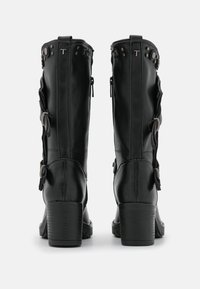 Czarne skórzane kozaki do kolan z grubym obcasem, z bocznymi zamkami i ozdobnymi detalami. Posiadają metalowe ćwieki i kokardki po bokach.