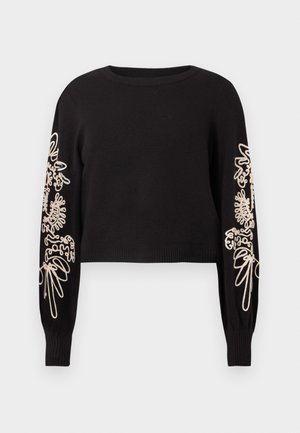 Suéter negro cortado con mangas largas, que presenta bordados florales en color beige en las mangas, cuello redondo y puños acanalados. Textura de tela suave.