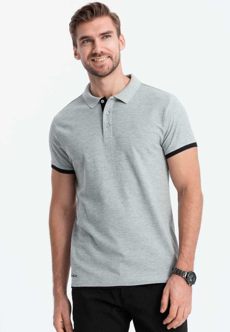 Polo gris con un cuello negro y acentos en las mangas, que cuenta con una tapeta de tres botones y un logo bordado en el dobladillo. Material de mezcla de algodón.