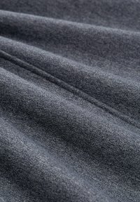 Grijze gebreide stof met zichtbare textuur en zachte plooien, die de materiaaldetails en het weefpatroon benadrukt.