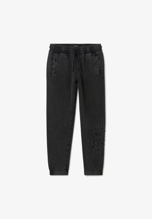 Zwarte joggingsbroek van zachte stof met een elastische tailleband, zijzakken en een gestructureerd grafisch detail op één pijp.
