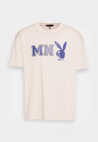 Beige kortärmad T-shirt med blå "MN" bokstäver och en blå Playboy-kaninlogotyp med fluga på bröstet.