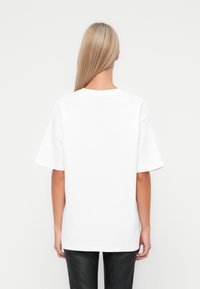 Bílé oversized tričko s kulatým výstřihem, krátkými rukávy a jednoduchým designem, vyrobené z měkké bavlny.