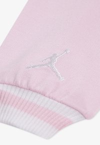 Rozā zeķe ar baltām svītrām pie malas, ar izliekto baltu Jumpman logo. Izgatavota no mīksta, elastīga auduma komfortam.