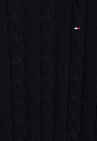 Maglione navy a maglia grossa, realizzato in tessuto spesso, con motivi testurizzati e un piccolo accento di logo rosso, bianco e blu sul petto.