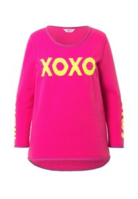 Rosa Pullover mit "XOXO" in Gelb auf der Vorderseite und gelben Akzenten an den Ärmeln. Weicher, gestrickter Stoff, runder Ausschnitt.