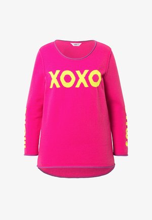 Vaaleanpunainen neulepaita, jossa on keltainen "XOXO" -teksti etupuolella ja keltaiset yksityiskohdat hihoissa. Pehmeä neulottu kangas, pyöreä pääntie.