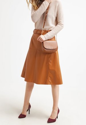 Brun mockaläder A-linje kjol med sidosömmar, i kombination med en beige randig tröja och en brun axelväska. Vinröda klackar fulländar looken.