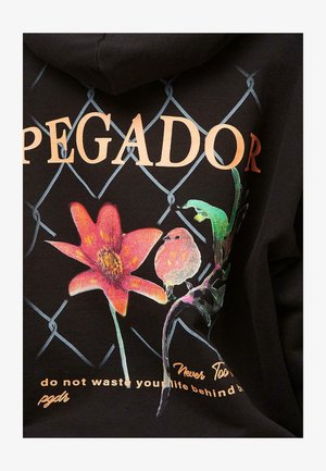 Čierna mikina s kapucňou s kvetinovým vzorom v červenej a ružovej farbe, s farebným vtákom a štýlovým textom na prednej strane. Pozadie má vzor reťaze.