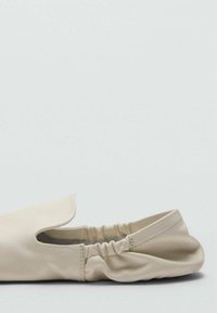 Beżowy skórzany but wsuwany z zaokrąglonym noskiem, elastycznym otworem i minimalistycznym designem. Gładka faktura z subtelnymi detalami szwów.