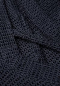 Tejido de punto en azul marino oscuro que presenta un patrón texturizado de tejido abierto con hilos visibles y un aspecto suave y flexible.
