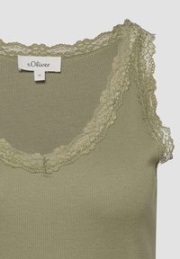 Haut sans manches en maille côtelée de couleur vert olive avec bordure en dentelle autour de l'encolure et des emmanchures, portant une étiquette de la marque s.Oliver indiquant la taille 36.