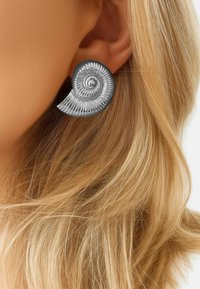 Pendientes de espiral plateados con un diseño texturizado que recuerda a una concha de nautilus. Presentan un acabado suave y un destacado detalle en espiral.