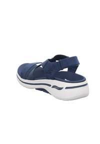 Sandalo blu navy con cinturini incrociati, supporto arco imbottito e base bianca. Presenta una suola testurizzata e cinturino per il tallone regolabile.