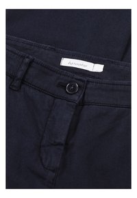 Marinblå tygbyxor med knappstängning, bälteshällor och en etikett med varumärket "hessnatur" sydd inuti midjebandet.